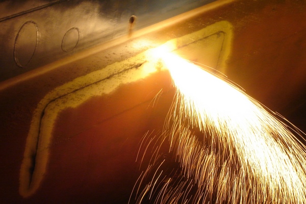 Sparks on the water - a plasma cutter works from the inside to make a hole in the hull